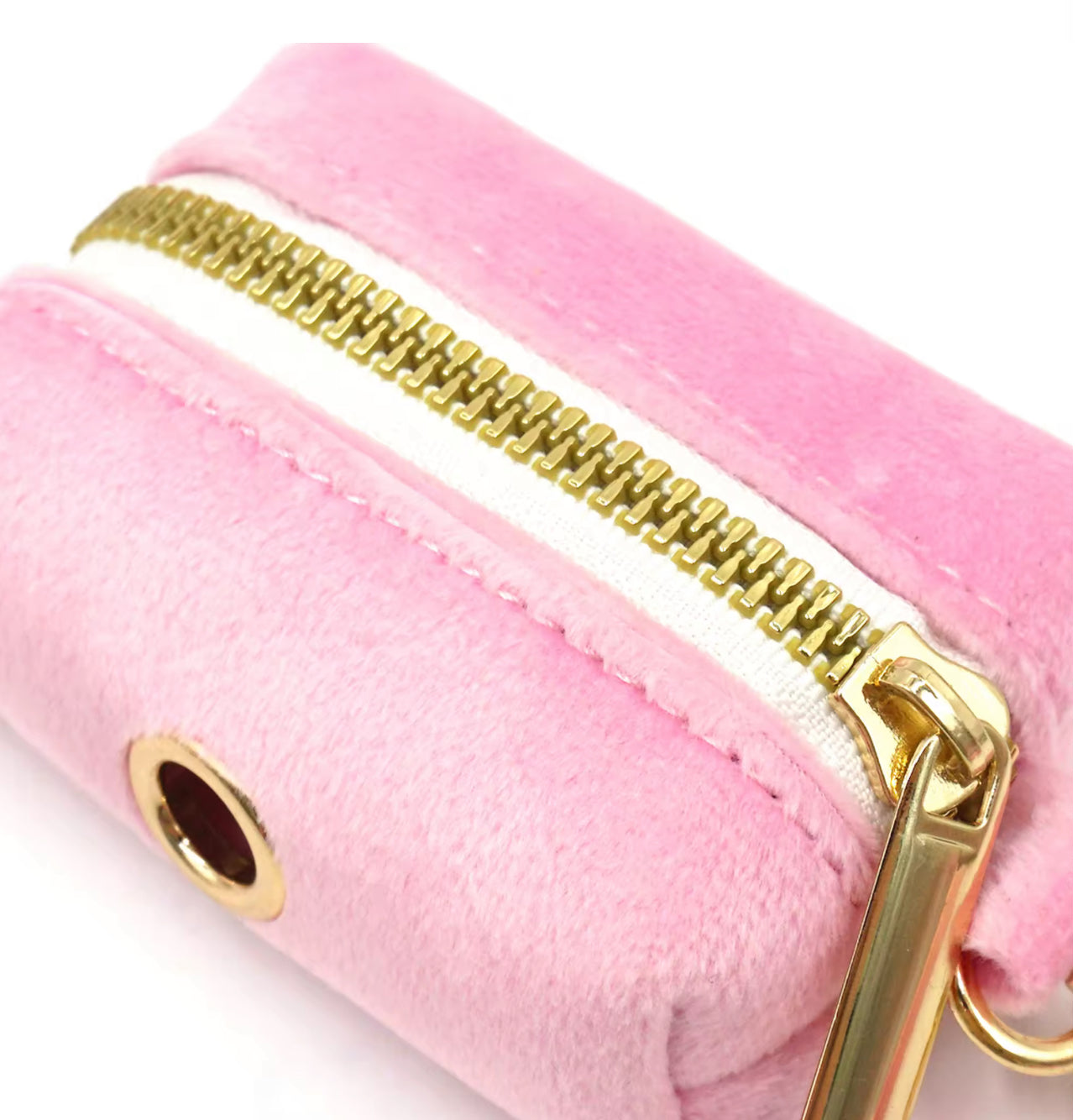 Close-up of a pink plush waste bag holder with a gold zipper on a white background